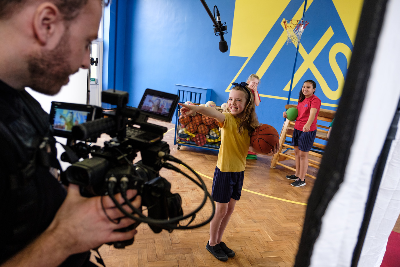 A cameraman films three young performers 