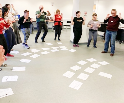 Workshop participants standing in front of loose paper on the floor.