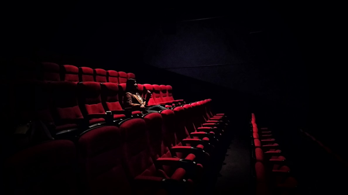 Woman sitting alone in theatre with red seats