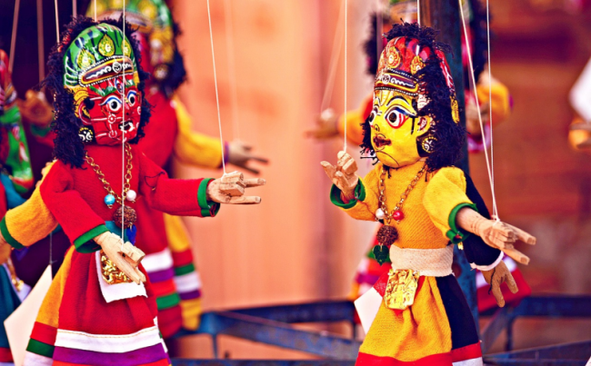 Two string puppets - one red and one yellow - face each other